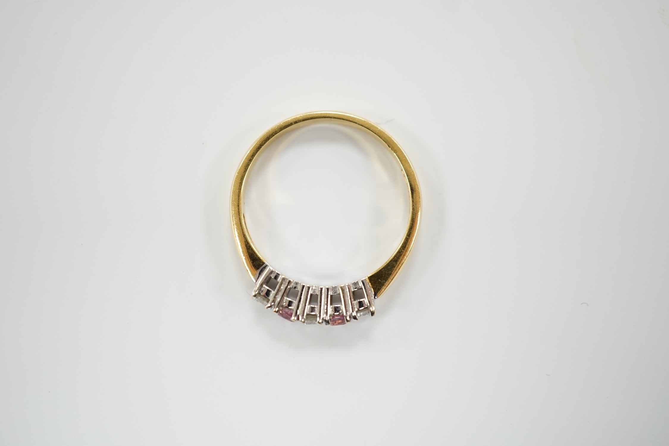 An 18ct gold, two stone pink sapphire? and three stone diamond set half hoop ring, size O, gross weight 3.3 grams.